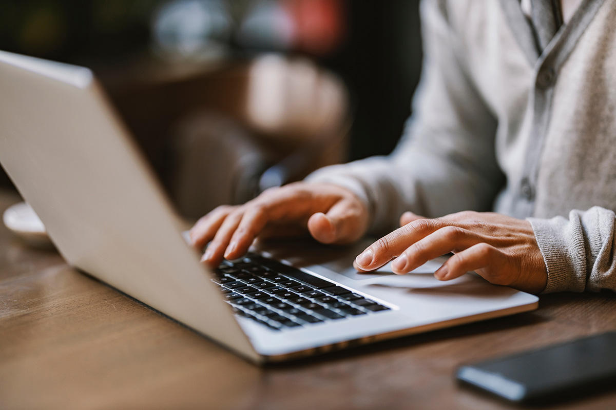 Hands typing on a laptop during online training.
