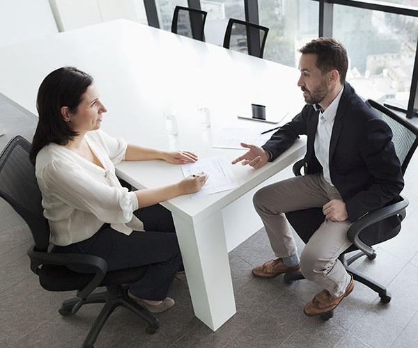 Woman and man in discussion at conference room table.